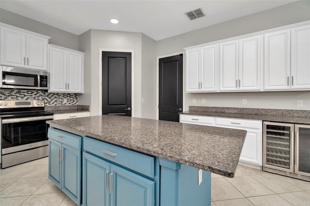 kitchen with light tile patterned flooring, blue cabinets, visible vents, white cabinets, and appliances with stainless steel finishes