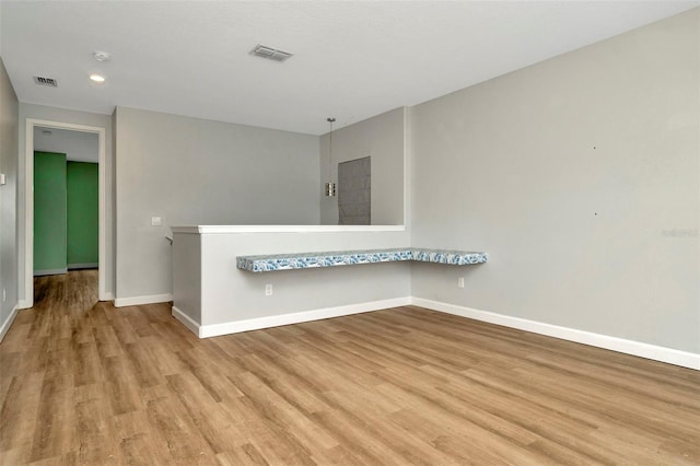 empty room with light wood-type flooring, baseboards, and visible vents