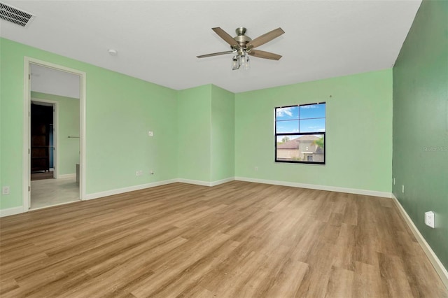 empty room featuring a ceiling fan, light wood-type flooring, visible vents, and baseboards