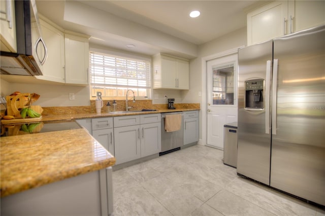 kitchen featuring light stone counters, recessed lighting, appliances with stainless steel finishes, white cabinets, and a sink