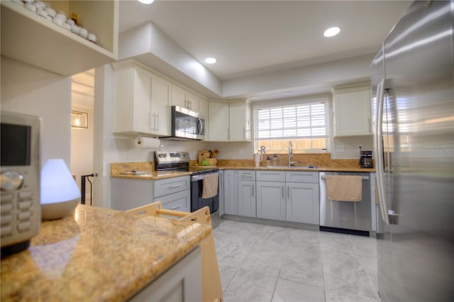 kitchen with light stone counters, stainless steel appliances, a sink, and recessed lighting