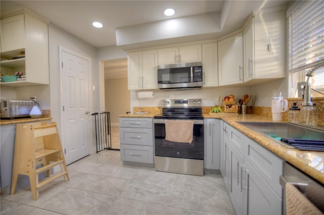 kitchen with appliances with stainless steel finishes, recessed lighting, a sink, and light stone countertops