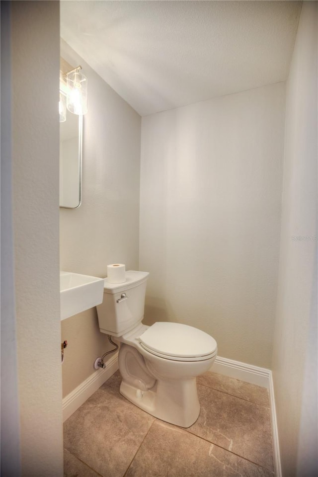 bathroom with tile patterned floors, toilet, and baseboards