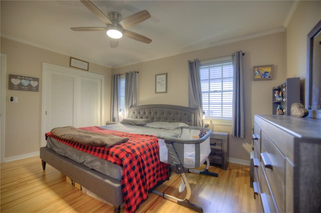 bedroom with crown molding, a closet, light wood-style floors, a ceiling fan, and baseboards