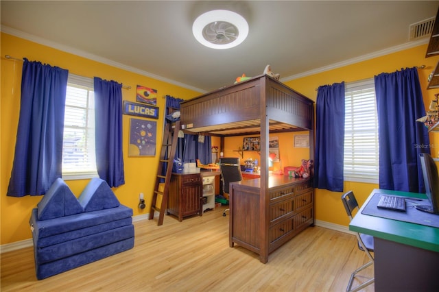 bedroom with baseboards, light wood-style flooring, visible vents, and crown molding