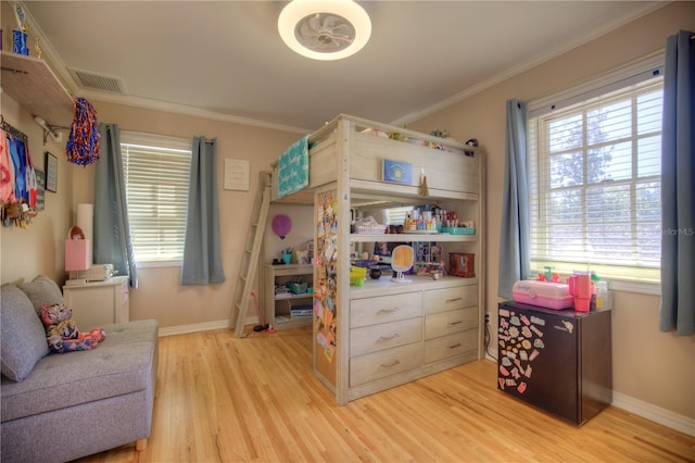 bedroom with ornamental molding, light wood-type flooring, visible vents, and baseboards