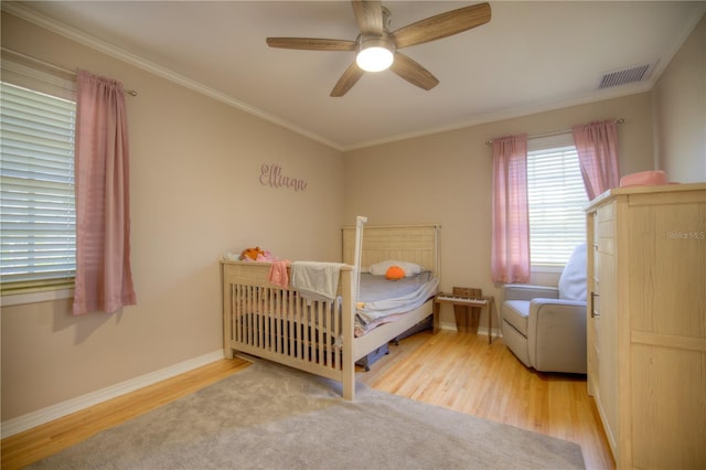 bedroom featuring baseboards, visible vents, a ceiling fan, ornamental molding, and wood finished floors