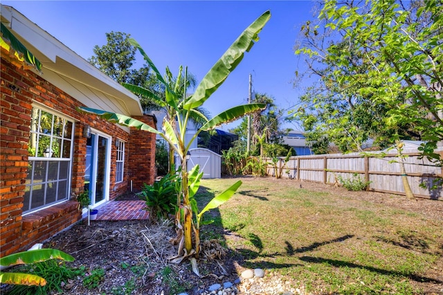 view of yard featuring a shed, an outdoor structure, and a fenced backyard