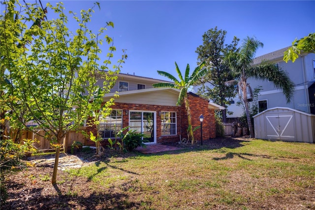 back of property featuring a storage shed, brick siding, an outdoor structure, fence, and a yard