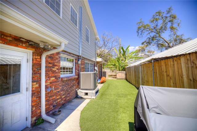 view of yard with central AC unit and fence