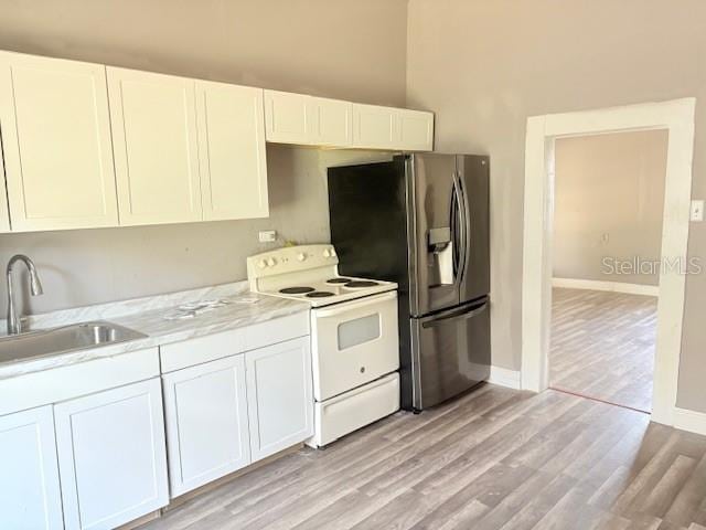 2410 Harper St, Tampa, FL 33605 - kitchen with light countertops, light wood-style flooring, white electric range, a sink, and stainless steel fridge with ice dispenser
