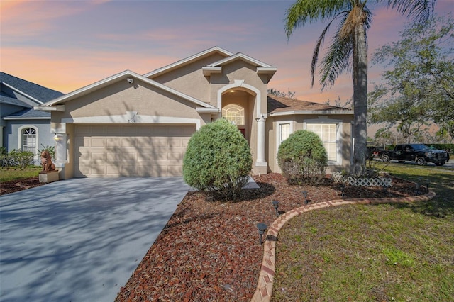 view of front of home with an attached garage, concrete driveway, and stucco siding