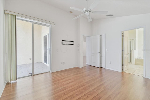 unfurnished bedroom featuring light wood finished floors, visible vents, vaulted ceiling, ensuite bath, and access to outside