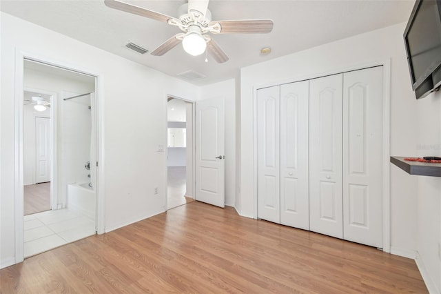 unfurnished bedroom featuring light wood-style floors, ceiling fan, visible vents, and a closet