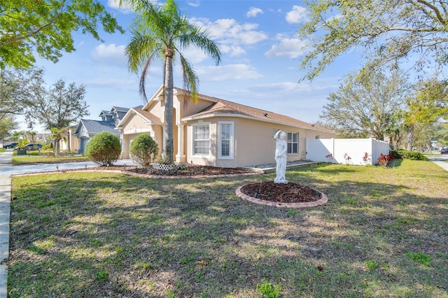 view of front of house featuring a garage, a front yard, fence, and stucco siding