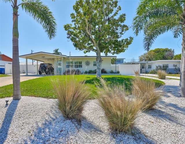 view of front of house featuring a carport, concrete driveway, a front yard, and fence