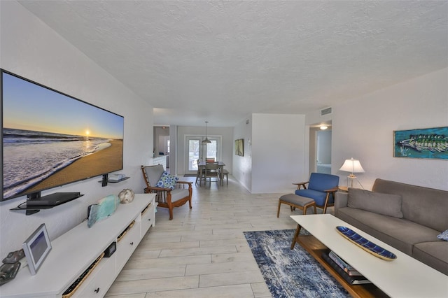 living area featuring visible vents, a textured ceiling, and light wood-style floors