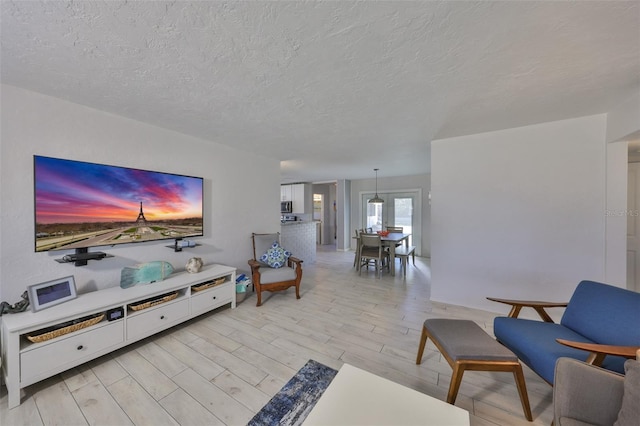 living area with light wood-style flooring and a textured ceiling