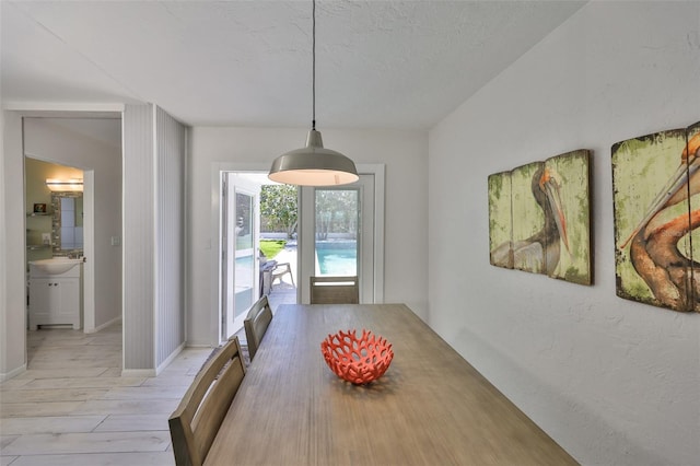 dining room with baseboards, light wood finished floors, and a textured ceiling