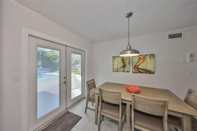 dining area featuring light wood-style floors, visible vents, and a textured ceiling