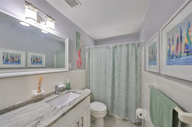 bathroom featuring visible vents, toilet, tile walls, and vanity