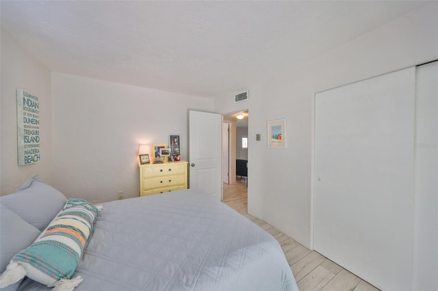 bedroom featuring visible vents, light wood-style floors, and a closet