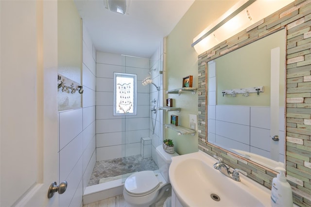 full bathroom featuring tiled shower, toilet, tile walls, and a sink