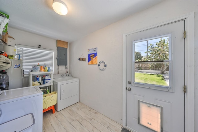 laundry area featuring light wood-type flooring, electric panel, electric water heater, separate washer and dryer, and laundry area