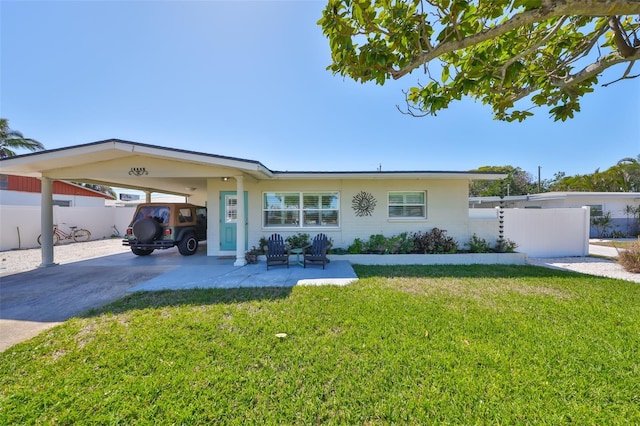 view of front of property featuring an attached carport, concrete driveway, fence, and a front lawn