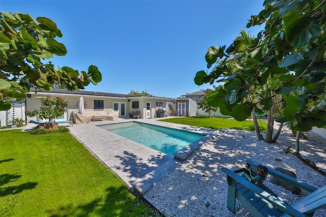 outdoor pool featuring fence, a shed, an outdoor structure, a patio area, and a lawn