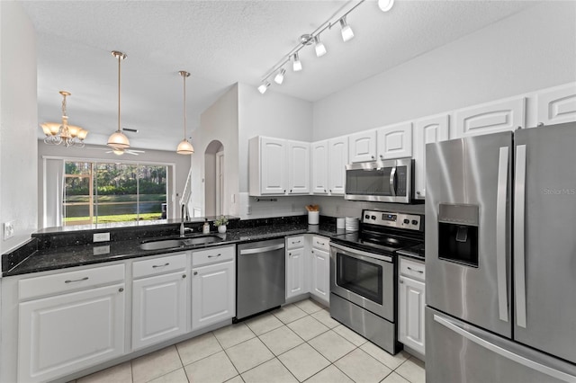 kitchen with a sink, white cabinetry, stainless steel appliances, arched walkways, and light tile patterned floors