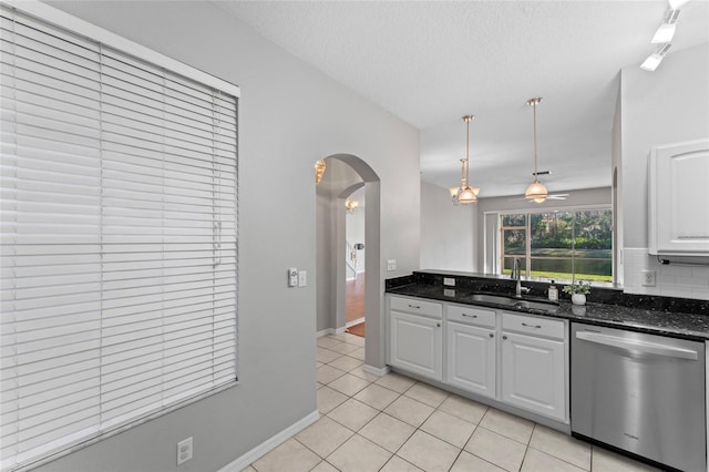 kitchen with a sink, stainless steel dishwasher, white cabinetry, arched walkways, and light tile patterned flooring