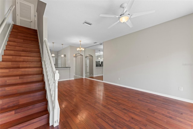 stairway featuring visible vents, baseboards, ceiling fan with notable chandelier, wood finished floors, and arched walkways