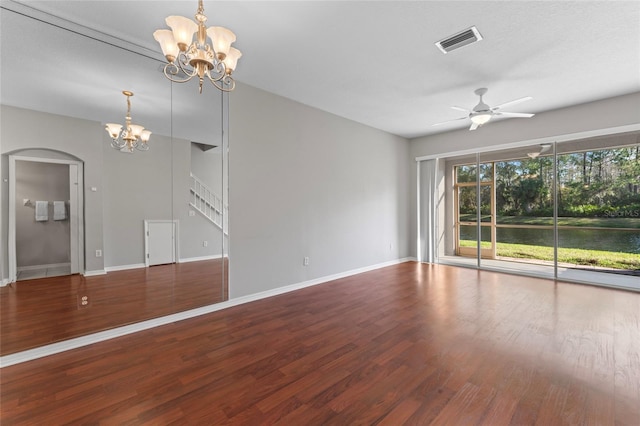 unfurnished living room with arched walkways, visible vents, ceiling fan with notable chandelier, and wood finished floors