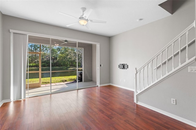 spare room featuring stairway, baseboards, ceiling fan, and wood finished floors