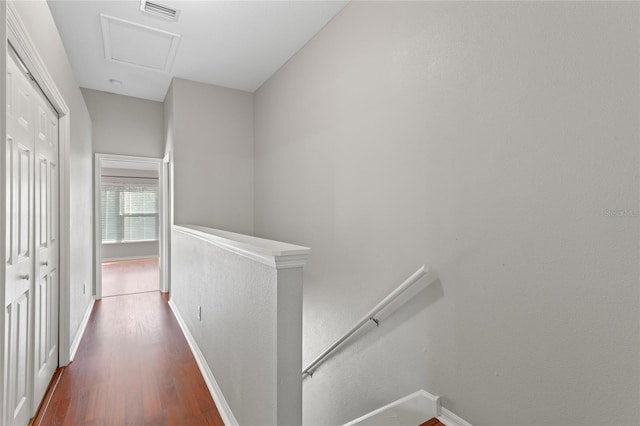 hall with visible vents, an upstairs landing, baseboards, attic access, and dark wood-style flooring