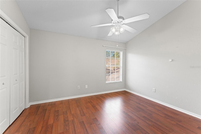 unfurnished bedroom with baseboards, lofted ceiling, wood finished floors, a closet, and a ceiling fan