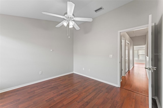 empty room with a ceiling fan, wood finished floors, visible vents, baseboards, and attic access