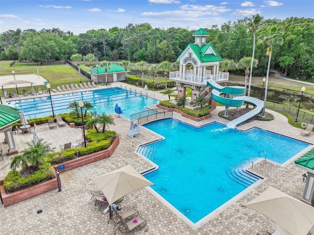 community pool featuring a patio, fence, and a water slide