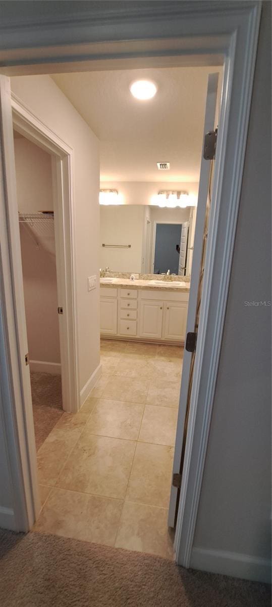 full bathroom featuring tile patterned floors, visible vents, a sink, double vanity, and a spacious closet