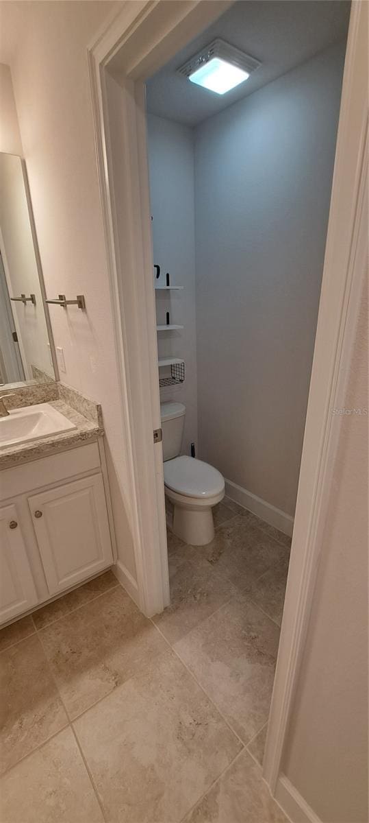 bathroom with baseboards, toilet, vanity, and tile patterned flooring