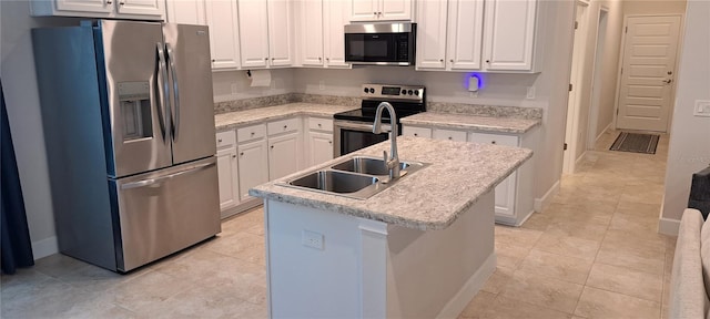 kitchen with a kitchen island with sink, a sink, stainless steel appliances, white cabinets, and light tile patterned floors