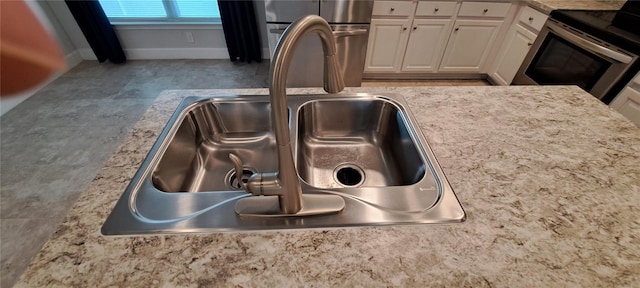 details with light countertops, electric stove, refrigerator, white cabinetry, and a sink