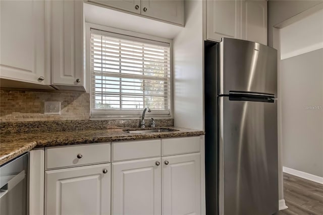 kitchen with tasteful backsplash, white cabinets, a sink, and freestanding refrigerator