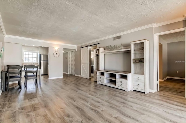 unfurnished living room featuring a barn door, baseboards, and wood finished floors