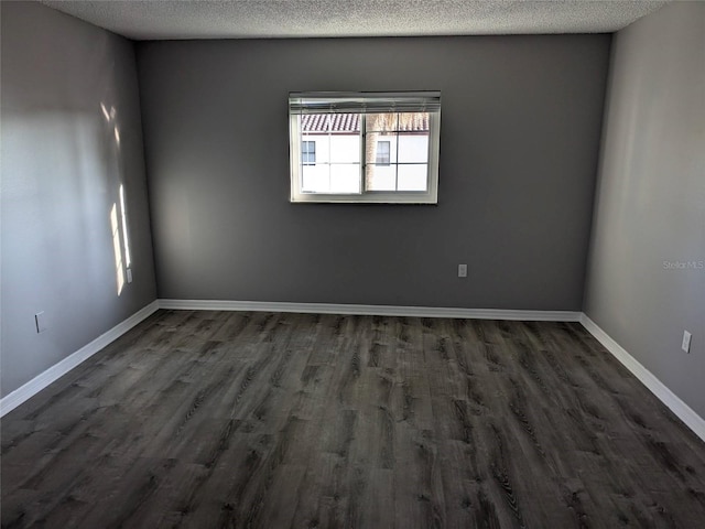 unfurnished room featuring a textured ceiling, dark wood finished floors, and baseboards