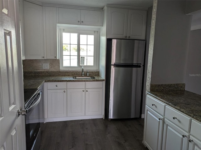 kitchen with dark wood-type flooring, a sink, white cabinetry, range, and freestanding refrigerator