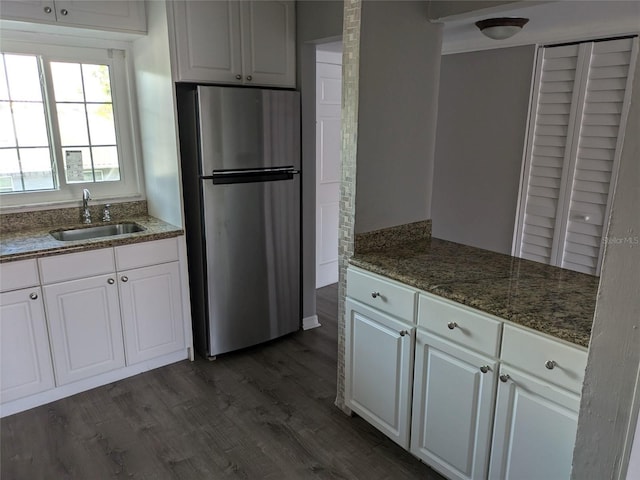 kitchen featuring dark wood-style flooring, a sink, white cabinetry, freestanding refrigerator, and dark stone countertops