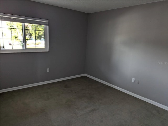 unfurnished room with baseboards, dark colored carpet, and a textured ceiling