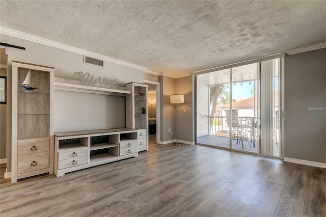 unfurnished living room featuring ornamental molding, wood finished floors, visible vents, and baseboards